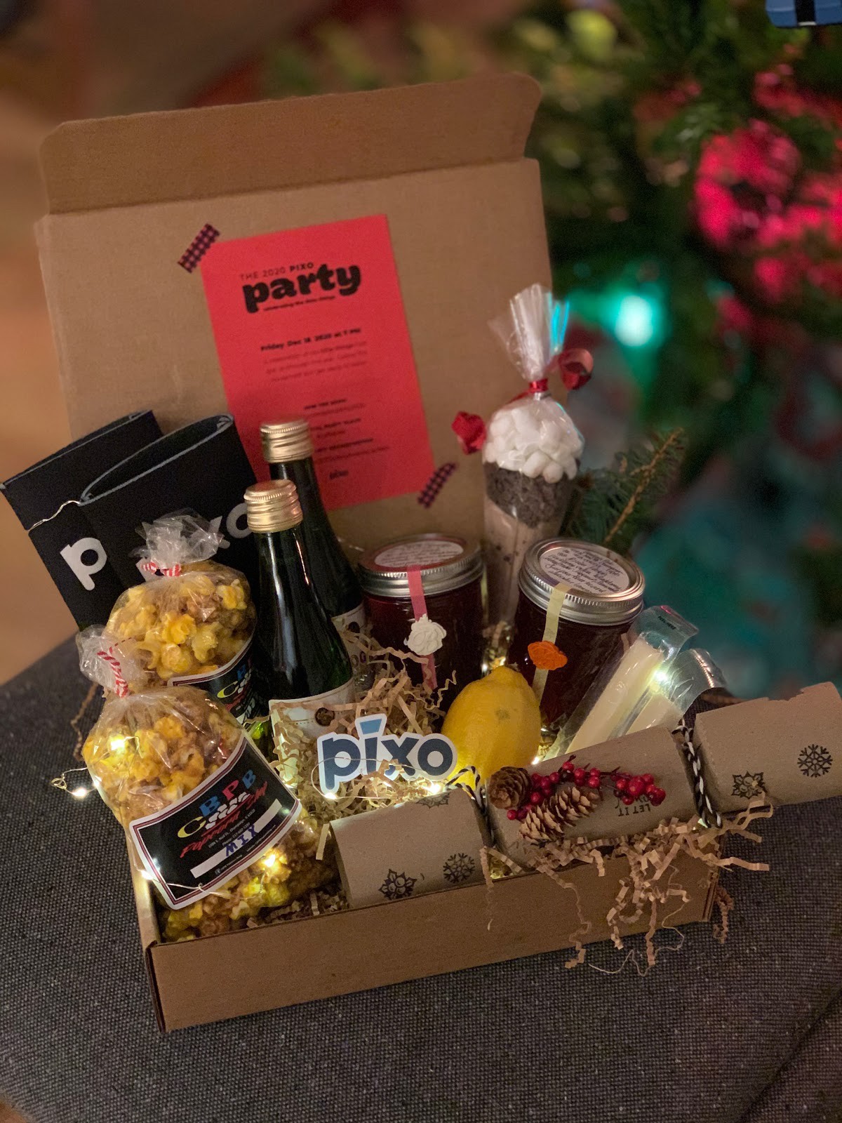 A box full of snacks, little champagne bottles, and a Pixo sticker.