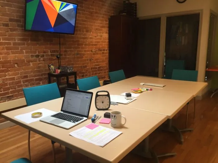 A conference table and chairs, with a laptop and supplies spread out.