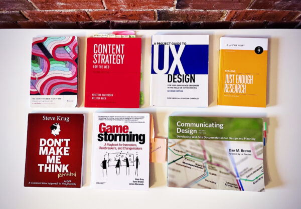 An aerial view of seven UX-related books on a white tabletop
