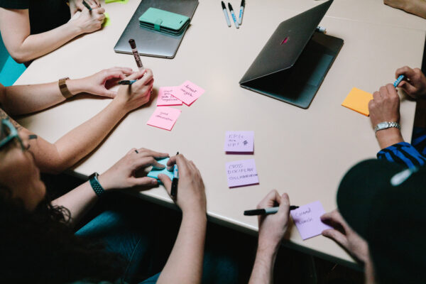 Aerial view of four people at a table writing on Post-it notes