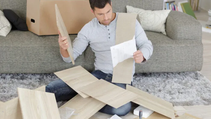 Man looking frustrated while assembling a piece of wood furniture