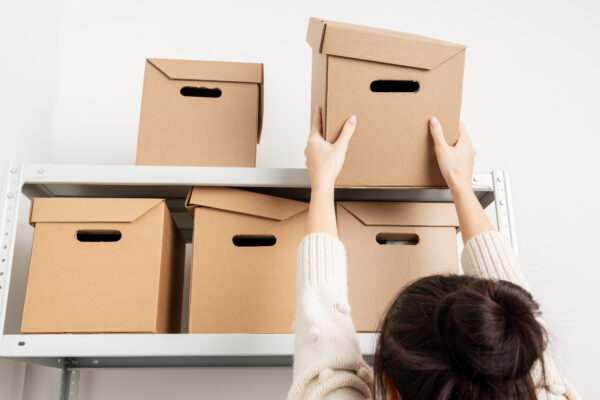 Woman taking a box off the top shelf