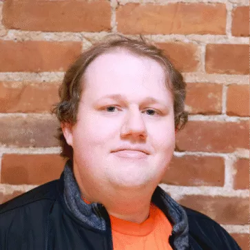 Andrew, a man with short blonde hair wearing an orange shirt and a black jacket