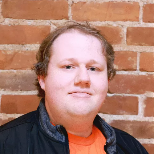Andrew, a man with short blonde hair wearing an orange shirt and a black jacket