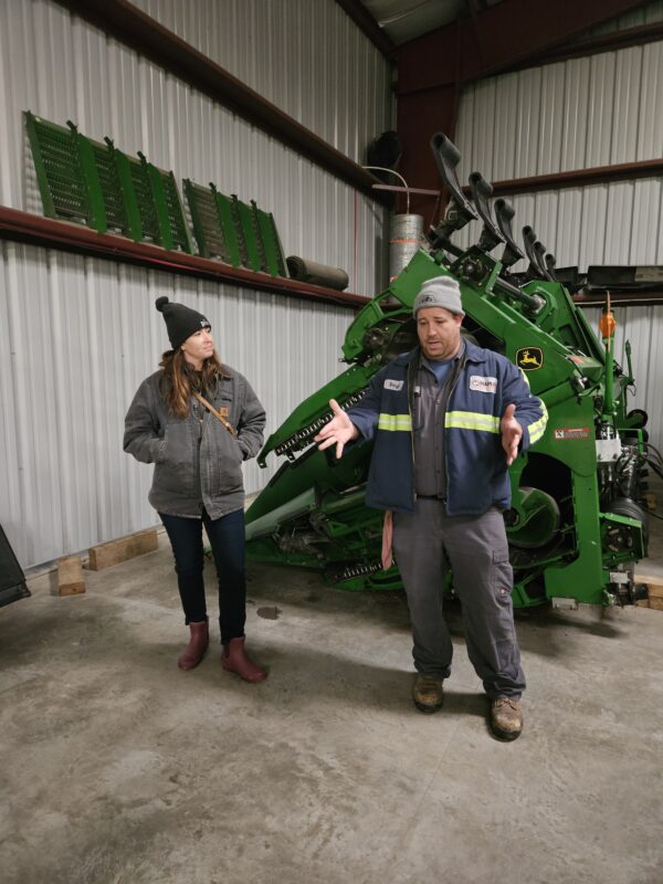 Danielle Hendricks and a farmer in front of a combine