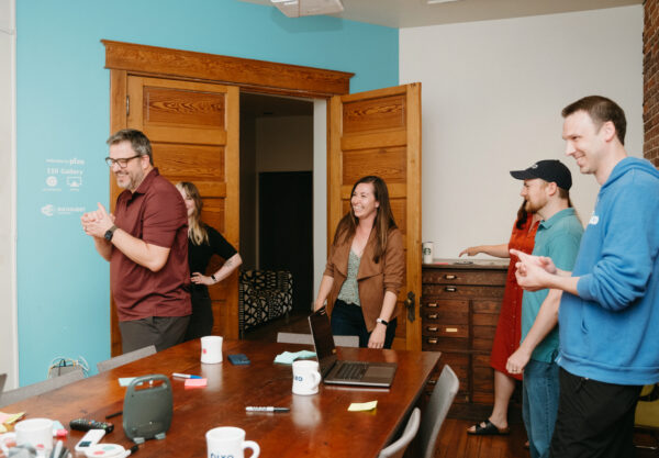 Pixo coworkers laughing and chatting in a office meeting room.