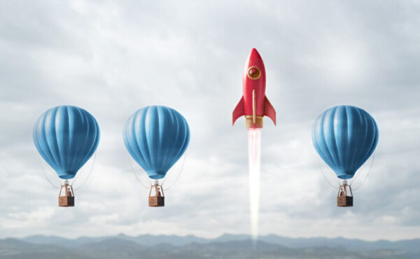 Three hot air balloons all at the same height and one rocket ship that is blasting off higher than the balloons. 