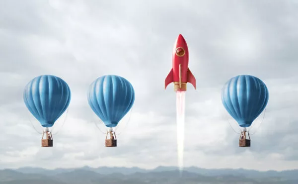 Three hot air balloons all at the same height and one rocket ship that is blasting off higher than the balloons.