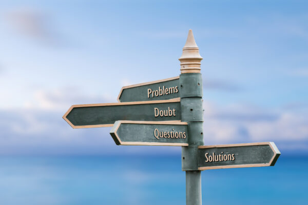 Problems, doubt, questions, solutions. Four word quote written on fancy steel signpost outdoors by the sea. Soft Blue ocean bokeh background.