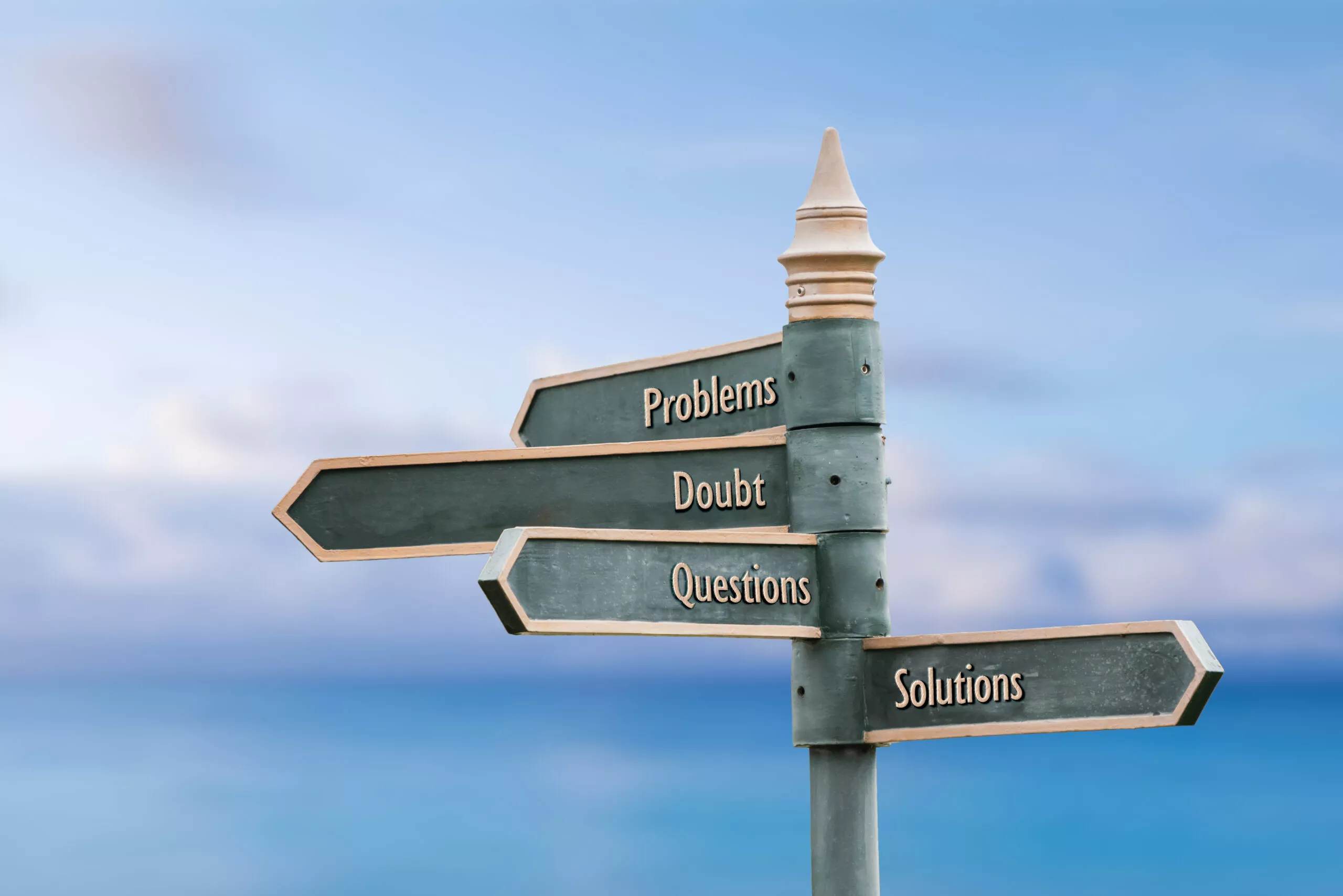 Problems, doubt, questions, solutions. Four word quote written on fancy steel signpost outdoors by the sea. Soft Blue ocean bokeh background.