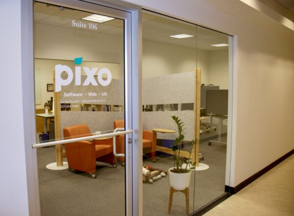 Glass door to Pixo's new office with lettering on the door that says Pixo - software, web, UX