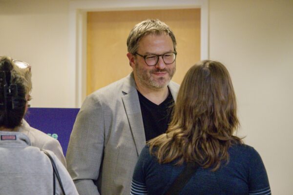 Jason Berg talking to a woman whose back is turned to the camera.