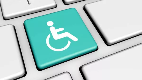 Close-up of a computer keyboard with a teal key featuring a wheelchair accessibility icon.