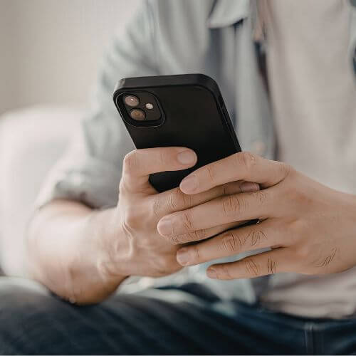 Close-up of a person using a black smartphone, holding it with both hands.