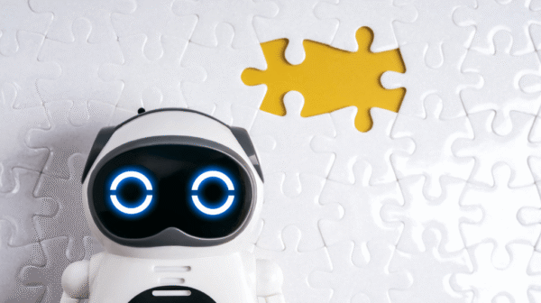 AI robot toy in front of a white puzzle piece background with a yellow cutout where a piece is missing.